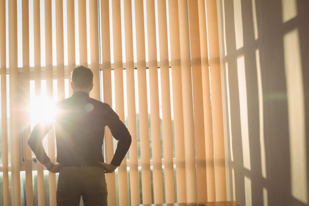 man standing with hands hip near window blinds